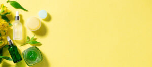 Flat-lay of skincare dropper bottles and cream jars on a yellow background with fresh leaves, representing micellar water and makeup-remover OEM manufacturing in Malaysia.