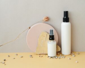 Spray-pump fragrance and body spray bottles styled with natural stone and pebbles, representing OEM body spray and fragrance mist manufacturing in Malaysia