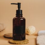 Amber glass pump bottle styled with natural bath accessories, representing OEM/ODM sunscreen and sun care product manufacturing in China