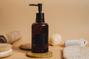 Amber glass pump bottle styled with natural bath accessories, representing OEM/ODM sunscreen and sun care product manufacturing in China