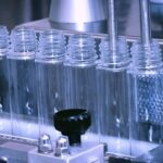 Empty plastic bottles moving along an industrial filling line, representing OEM/ODM home care and household cleaning product manufacturing in China