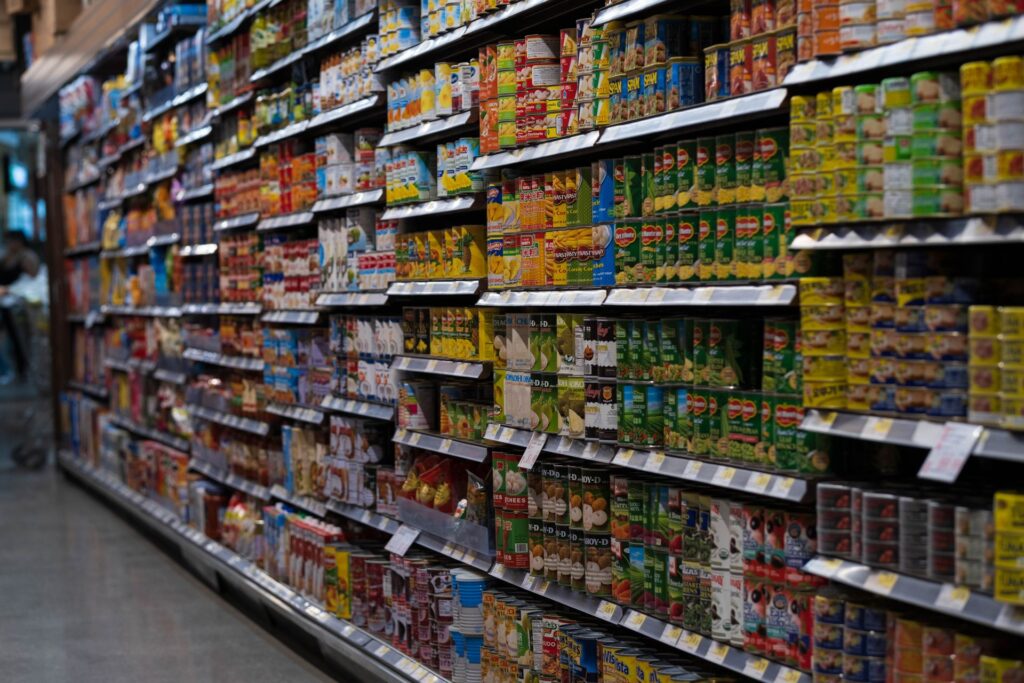 Grocery and mini-market shelves stocked with packaged food products, representing Hung Tai Group's wholesale and retail food business acquired by Life Water Berhad