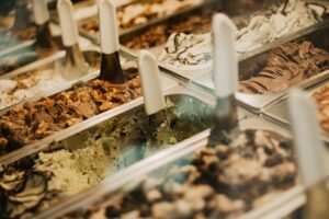 Tubs of artisanal ice cream and gelato in a parlour display case, illustrating Farm Fresh's acquisition of The Inside Scoop ice cream chain