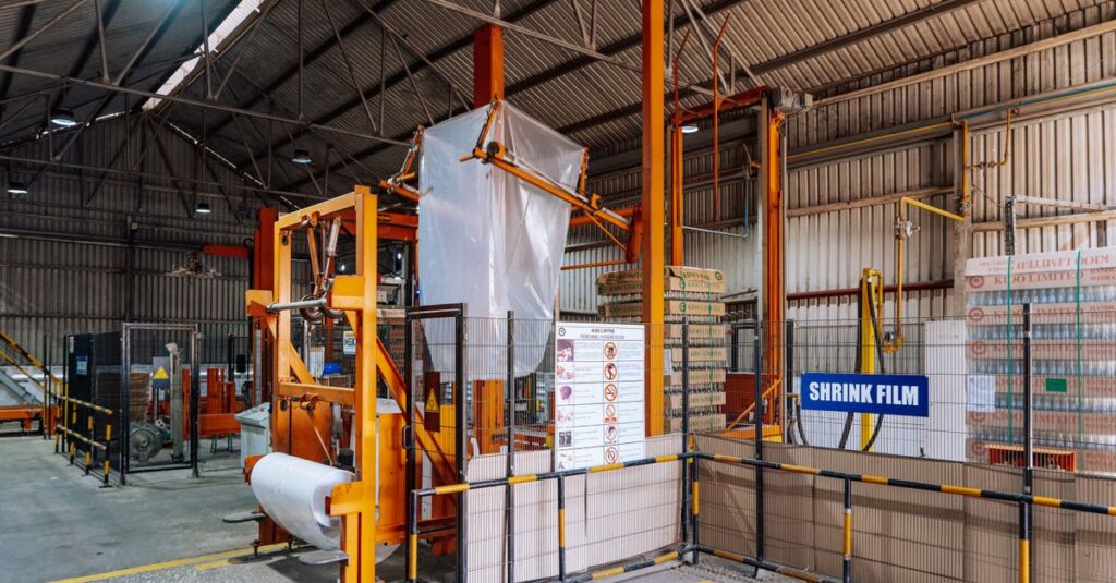 Industrial packaging warehouse with shrink film wrapping machine, representing Scientex Berhad's flexible and industrial packaging manufacturing business