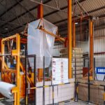 Industrial packaging warehouse with shrink film wrapping machine, representing Scientex Berhad's flexible and industrial packaging manufacturing business