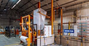 Industrial packaging warehouse with shrink film wrapping machine, representing Scientex Berhad's flexible and industrial packaging manufacturing business