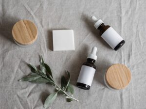 Unlabelled vegan skincare dropper bottles and bamboo-lid jars with a green sprig on linen, illustrating Vietnamese plant-based beauty brand Cocoon