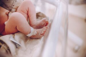 Newborn baby's feet with a hospital ID bracelet in a maternity ward bassinet, illustrating Thomson Medical Group's maternity and fertility hospital franchise